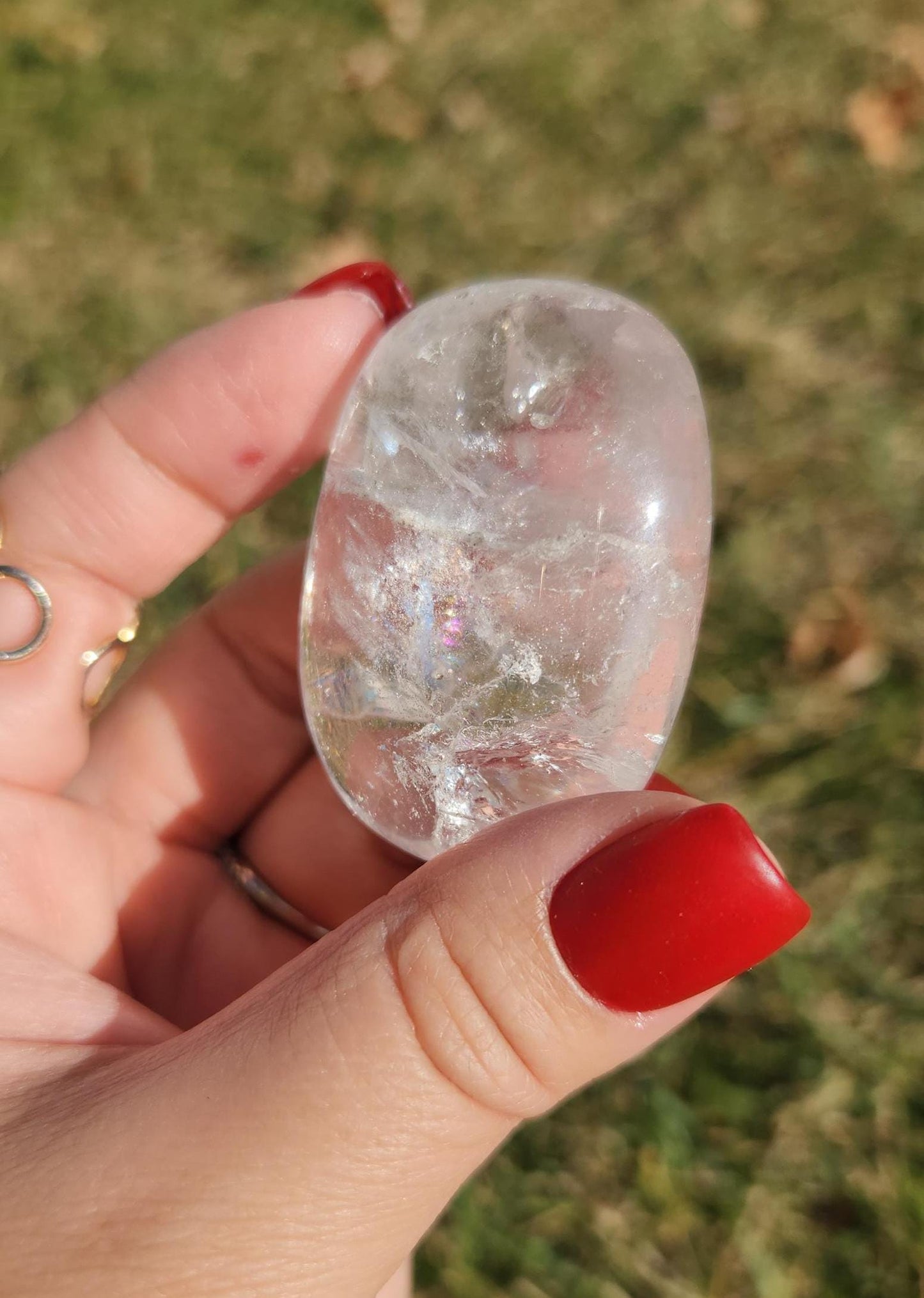 Beautiful natural lemurian clear quartz palm stone with inclusions and rainbows, from the Tocantins mine in Brazil