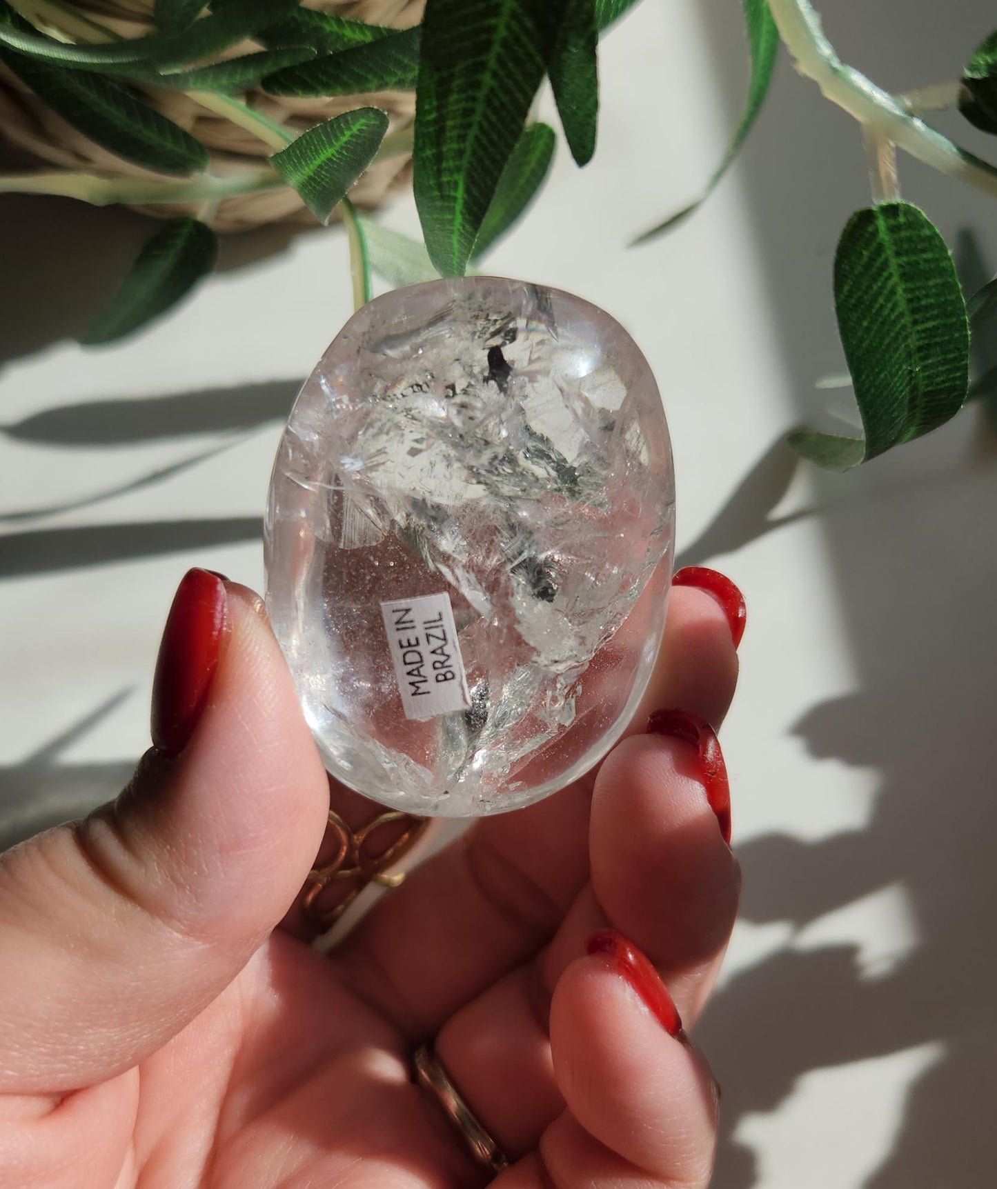 Stunning lemurian clear quartz palm stone with inclusions and shy rainbows, from the Tocantins mine in Brazil