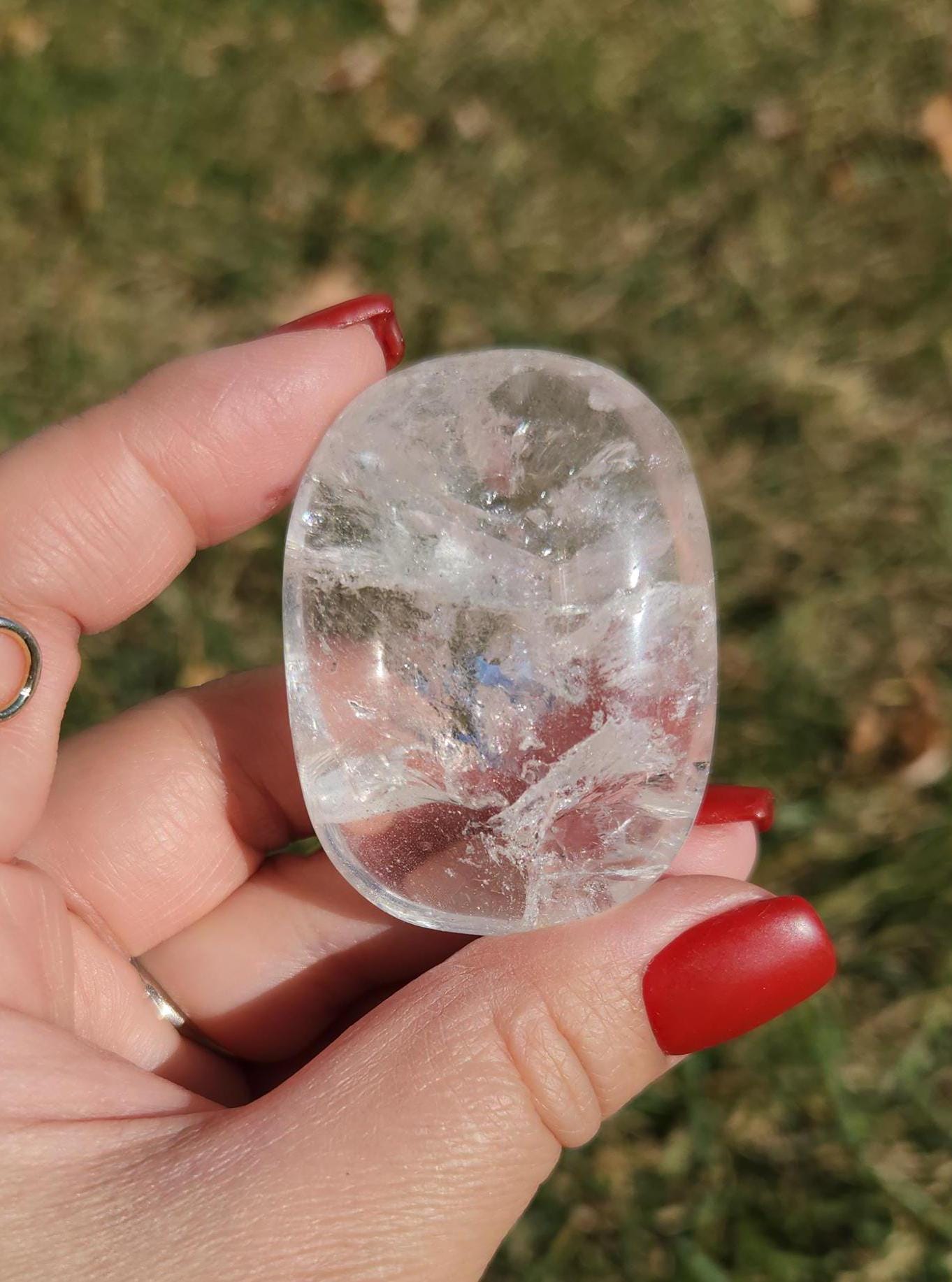 Beautiful natural lemurian clear quartz palm stone with inclusions and rainbows, from the Tocantins mine in Brazil