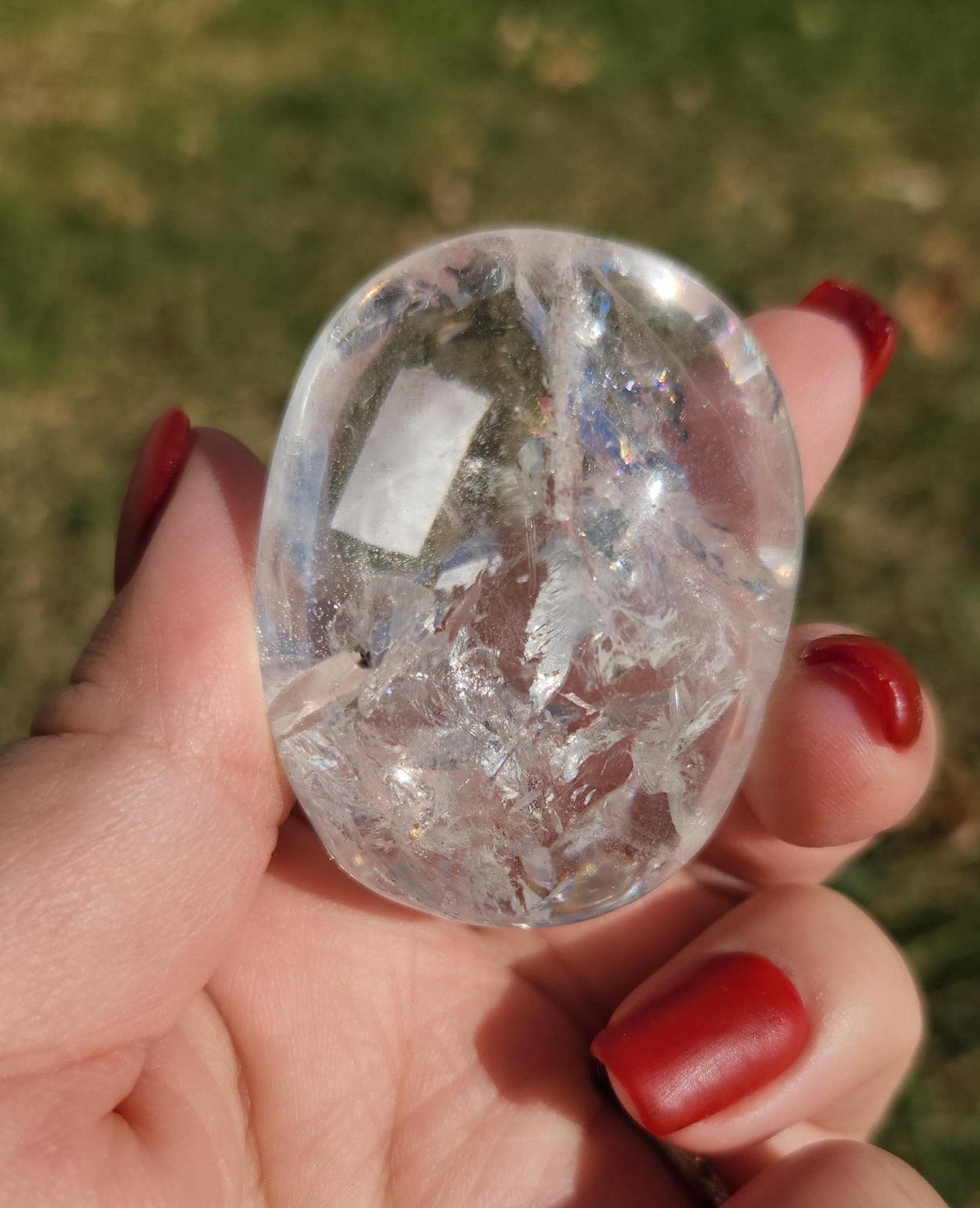 Stunning lemurian clear quartz palm stone with inclusions and shy rainbows, from the Tocantins mine in Brazil