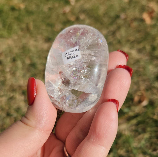 Beautiful natural lemurian clear quartz palm stone with inclusions and rainbows, from the Tocantins mine in Brazil
